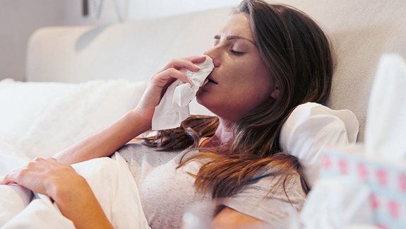 Frau liegt mit einer Erkältung im Bett